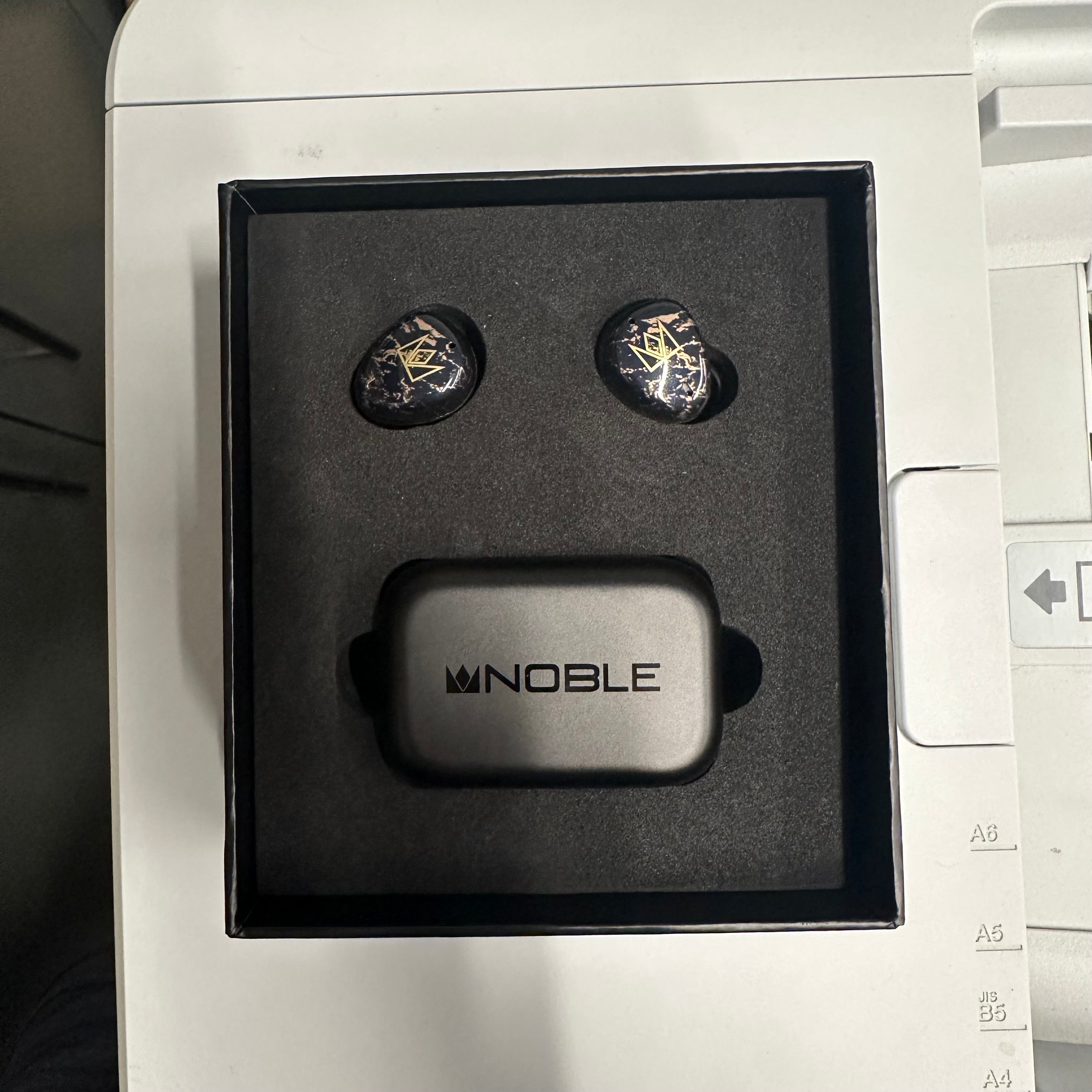 Noble fokus rex5 black earbuds in box on a grey surface