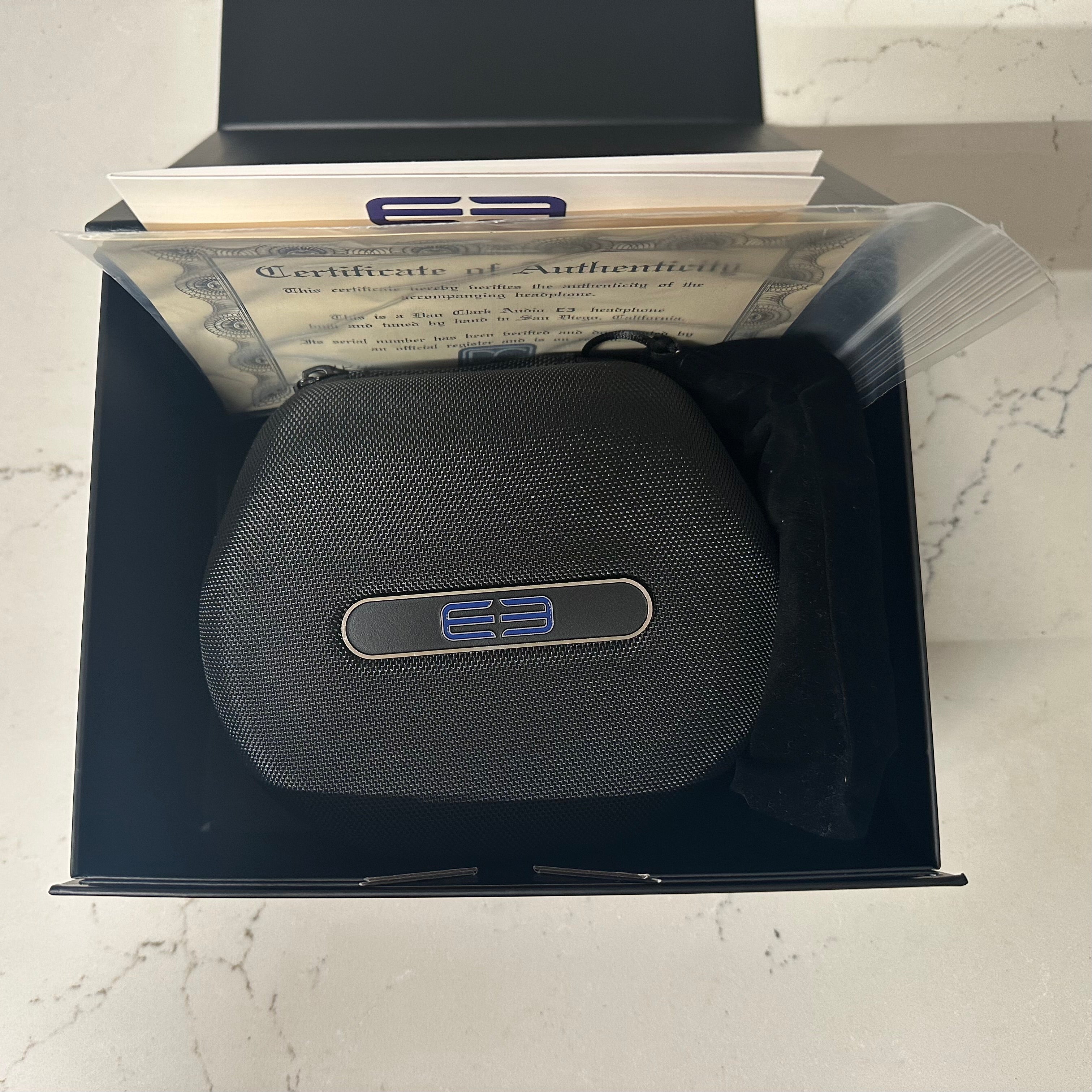 Black electronic device with a logo in a box with a certificate of authenticity on a marble surface