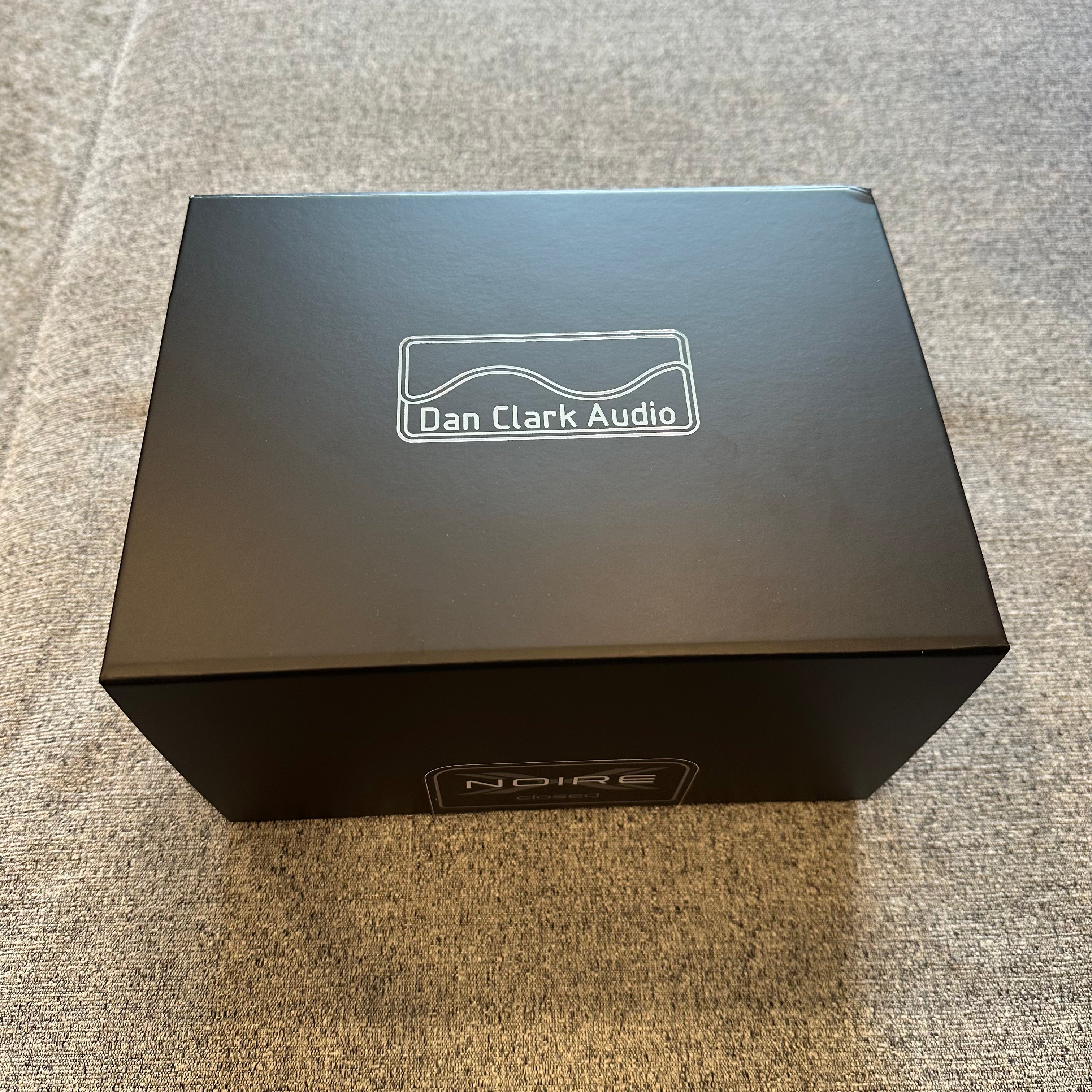 Black box with 'Dan Clark Audio' logo on a gray surface